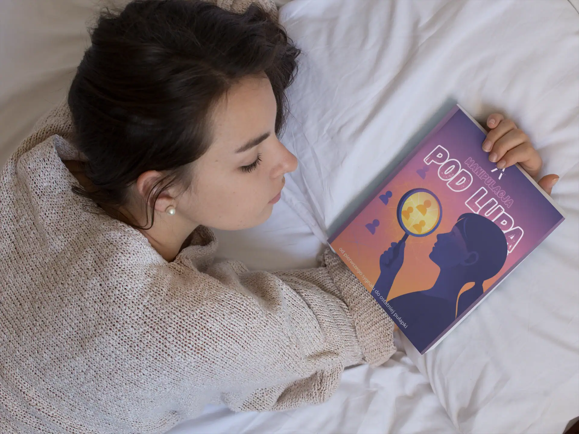 young-girl-holding-a-book-on-her-hand-while-lying-down-on-her-bed-mockup-a14275